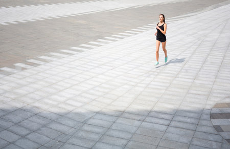 Woman Runs on a Patterned Pavement in a Large Open Space During Daylight Hours