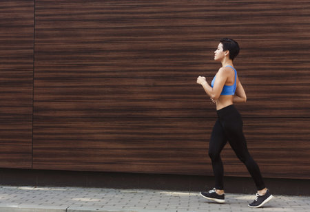 Woman Running Along a Wooden Wall During a Sunny Day in an Urban Setting