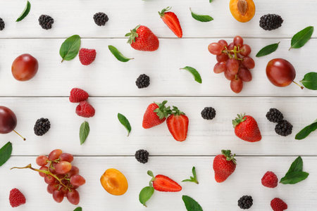 Assorted Fruits and Leaves Arranged on a Wooden Table for a Creative Display
