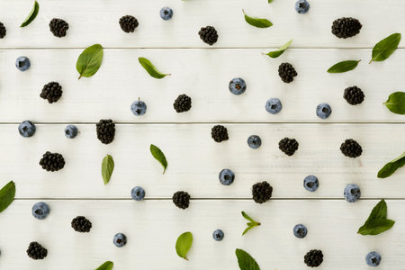 Collage of Blackberries, Blueberries, and Green Leaves Arranged on a Wooden Table