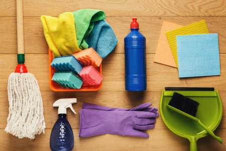 Collection of Cleaning Supplies Arranged on a Wooden Floor Showing Various Colors and Types
