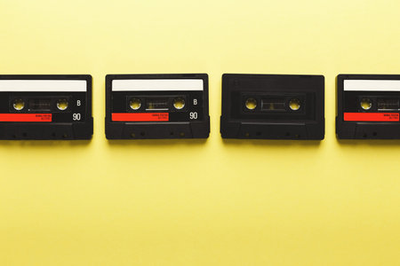 Collection of Old Cassette Tapes on a Yellow Background for Nostalgic Themes and Music Loversの写真素材