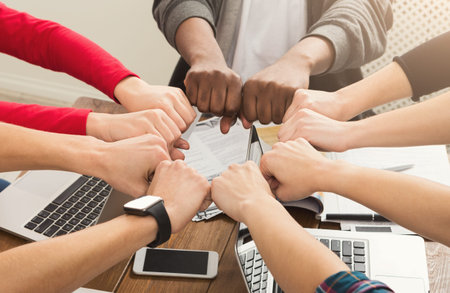 Hands Joining Together in a Collaborative Effort Around a Work Table in a Modern Setting