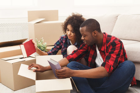 Couple Sorting Books in Boxes During a Home Move in a Living Room Setting