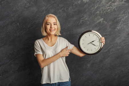 Smiling Woman Shows Clock in Collage Setting With Dark Background During Daytime Activity