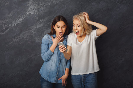 Friends React to Surprising News While Looking at a Mobile Phone in a Dark Setting