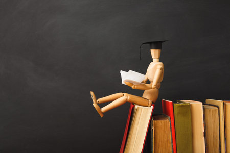Graduation Figure Reading on Top of Stacked Books in a Study Setting