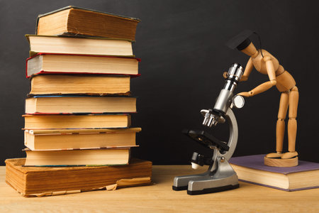Collage of Books and a Wooden Figure Using a Microscope on a Wooden Table