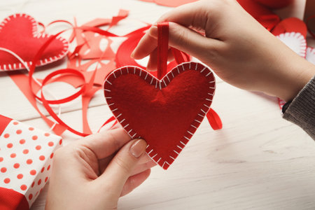 Hands Create Red Heart Ornaments for Decoration During Crafting Session