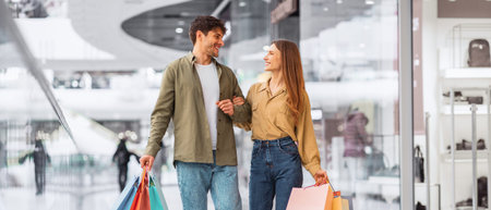 Couple Walks Together in Shopping Mall Holding Colorful Bags After a Day of Shopping