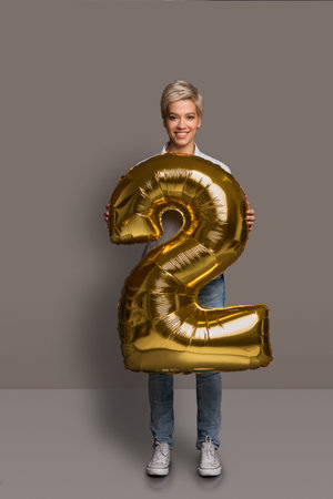 Collage Featuring a Person Holding a Large Golden Number Two in a Studio Setting