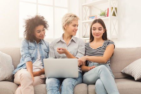 Friends Gathered Around Laptop Sharing Ideas and Enjoying Time Together Indoorsの写真素材