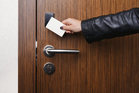 Hand Holds a Key Card While Approaching a Door With Wooden Finish and Metal Handle