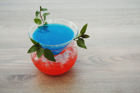 Bright Blue and Red Drink Served in a Rounded Glass on a Wooden Table With Ice Cubes