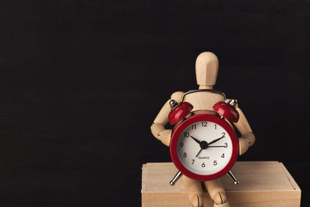 Wooden mannequin with red alarm clock