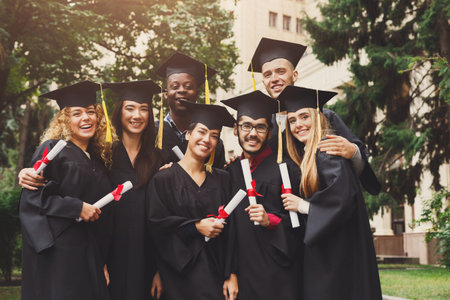 Group of Graduates Celebrate Achievement in Outdoor Setting With Diplomas in Handの写真素材