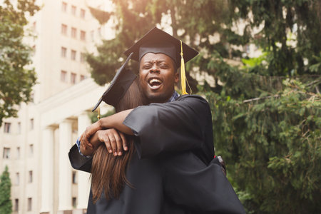 Graduates Hugging in Celebration Outside During Graduation Day in Sunny Weather at University