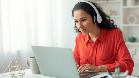 Woman Working on Laptop With Headset in a Bright Room During the Day