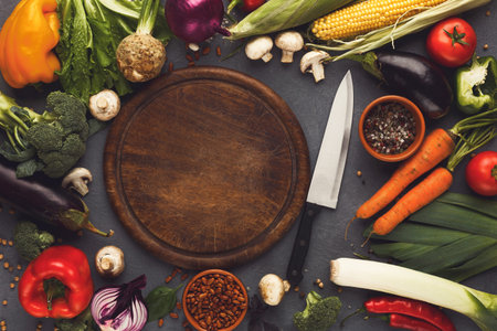 Collection of Fresh Vegetables and Kitchen Tools Arranged on a Wooden Cutting Board