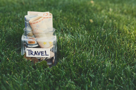 Collection of Money in a Jar for Travel Savings on Green Grass