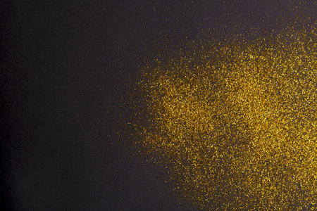Collection of Golden Glitter Scattered on a Dark Surface for Creative Projects and Crafts