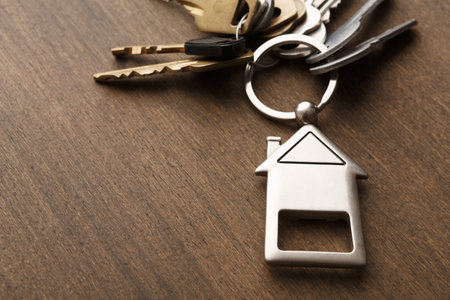Keys Arranged on a Wooden Table With a House-Shaped Keychain in a Simple Setup