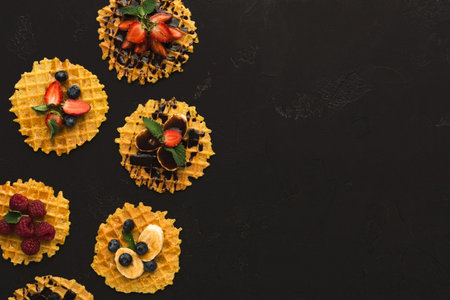 Collection of Waffles Topped With Fruits Arranged on a Black Surface During the Day
