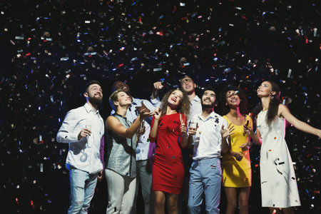 Group of Friends Celebrating Together Under Confetti During a Fun Event Night in a Venue