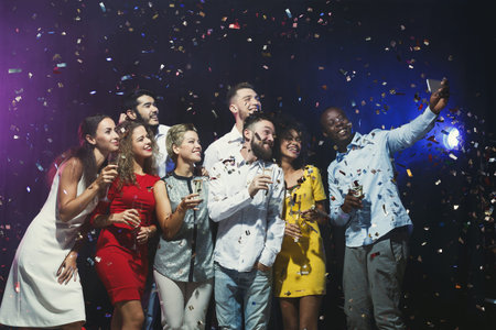 Group of Friends Celebrating With Drinks and Confetti During an Evening Event in a Party Setting