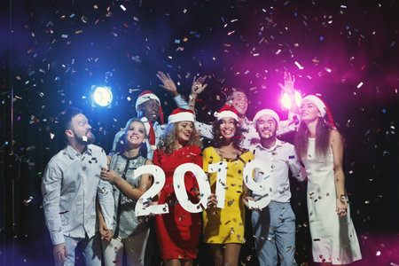 Group of People Celebrating New Year With Confetti and Hats in a Festive Setting