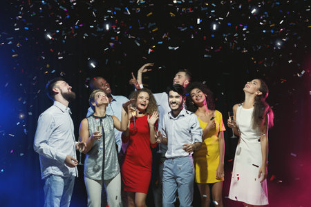 Group Celebrates Under Colorful Confetti During a Party at a Lively Venue With Friends at Night