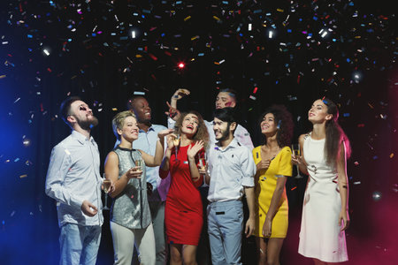 Celebration Event With a Group of People Enjoying Drinks and Confetti Falling at Night