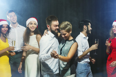 Group of Friends Enjoying a Festive Party While Wearing Holiday Hats and Celebrating Together