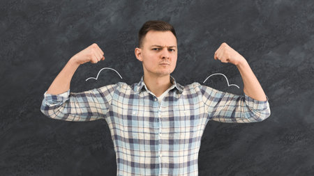 Young man with depicted muscles on chalkboard