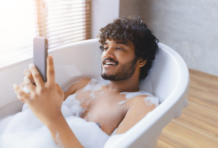 Man Relaxing in Bathtub While Using Smartphone During Afternoon