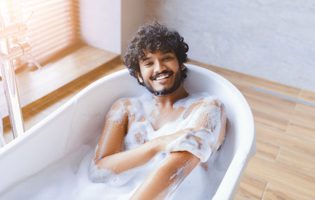 Young Man Enjoys Bubble Bath in Modern Bathroom With Natural Light During Afternoon