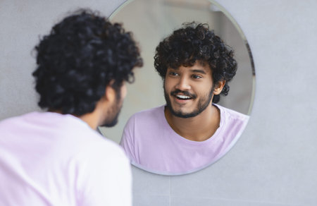Young Man Looking at His Reflection and Smiling in a Mirror During the Day