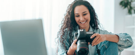 Woman Reviews Pictures on Camera While Sitting by Her Laptop in a Well-Lit Room