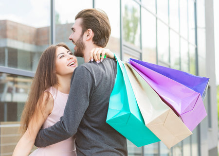 Young lovers hugging with shopping bags on the streetの写真素材
