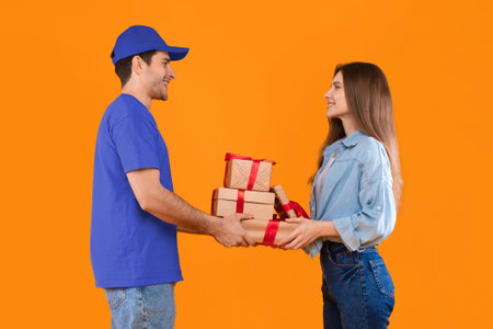 Delivery Person Hands Over Gifts to a Smiling Woman in Front of an Orange Background