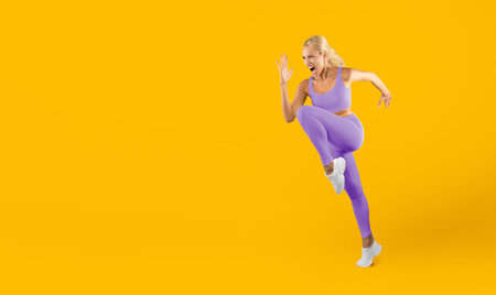 Woman Performs an Energetic Kick Against a Bright Yellow Background During a Workout Sessionの写真素材