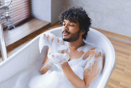 Man Relaxes in Bathtub Enjoying Bubbles During a Bath at Home in the Afternoon