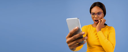 Woman Looks Surprised While Using Smartphone Against Blue Background