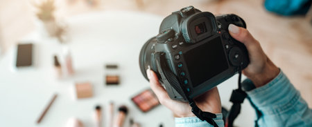 Hands Hold a Camera Capturing Makeup Products on a Table in a Bright Room During the Dayの写真素材