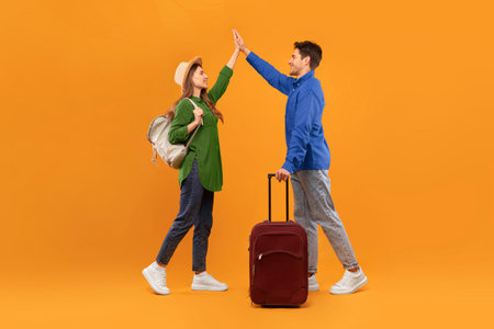 Friends Sharing a High Five During a Journey in Front of a Bright Orange Backgroundの写真素材