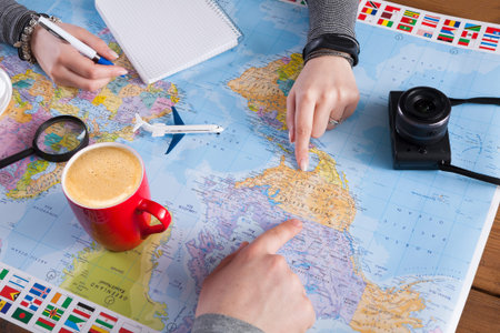 Planning a Trip With a Map, Camera, and Coffee at a Table With Flags and Notes