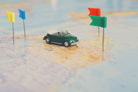 Small Green Toy Car on Map With Flags Marking Different Locations