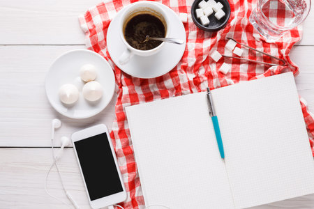 Simple Workspace Setup With Coffee, Journal, and Mobile Phone on a Checkered Tablecloth