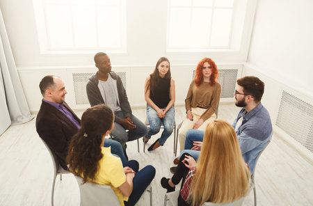 Group of People Engaged in a Discussion in a Bright Room During a Meeting
