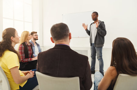 Man Speaking to a Group of People During a Workshop in a Bright Room